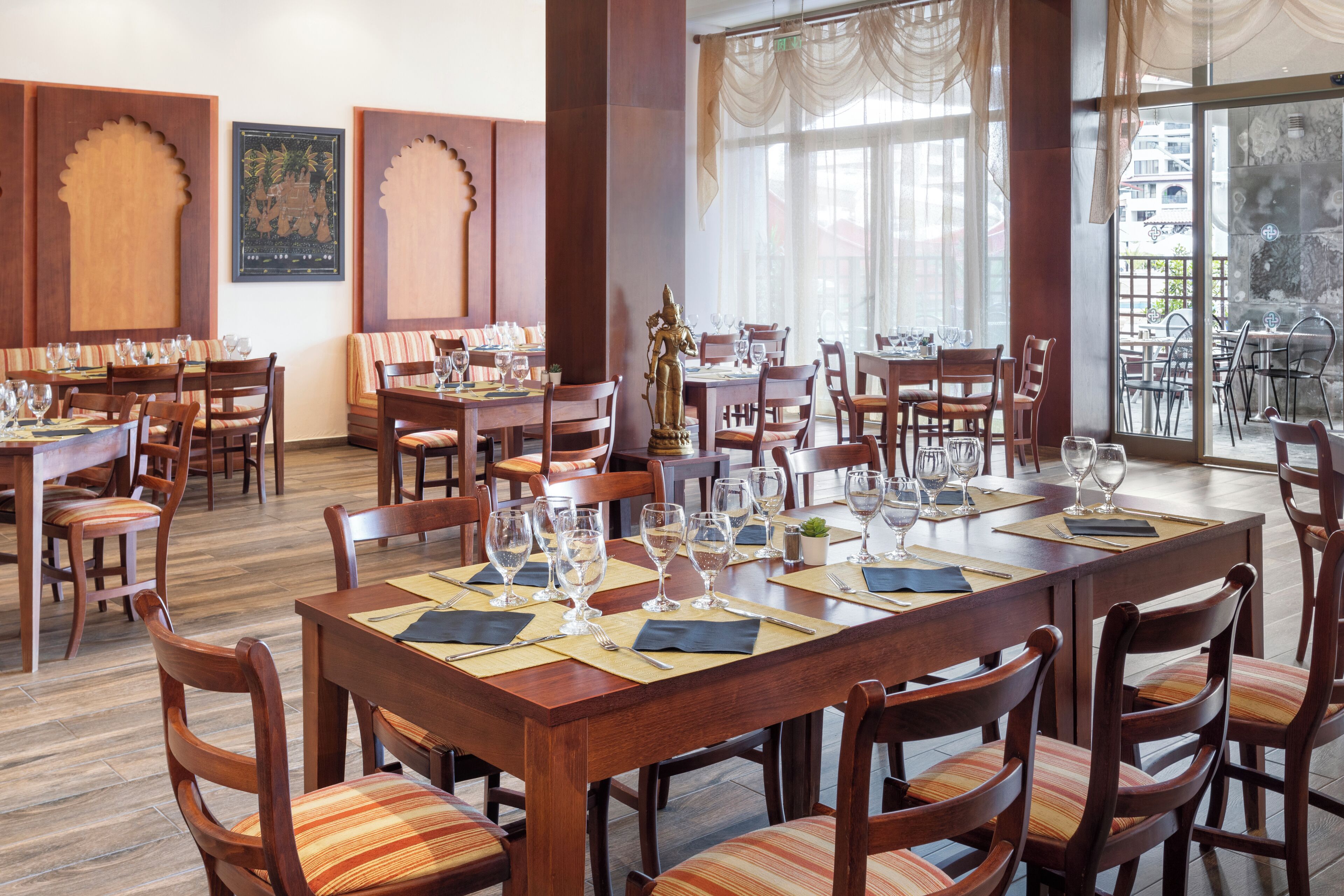 A restaurant with wooden tables and chairs, large windows, and a view of the city.