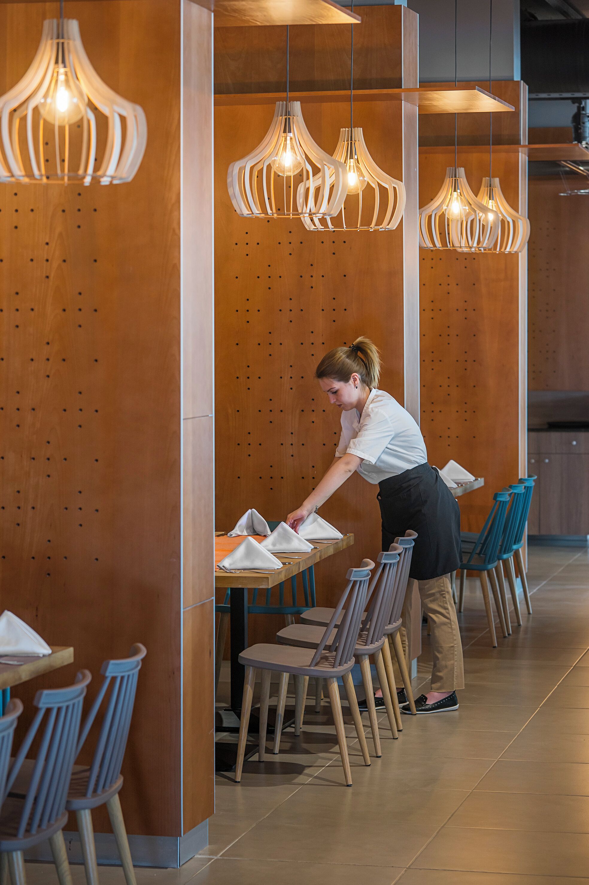 Ein Restaurantinneres mit Holzwänden, hängenden Pendelleuchten und Reihen aus Holzkästen.
