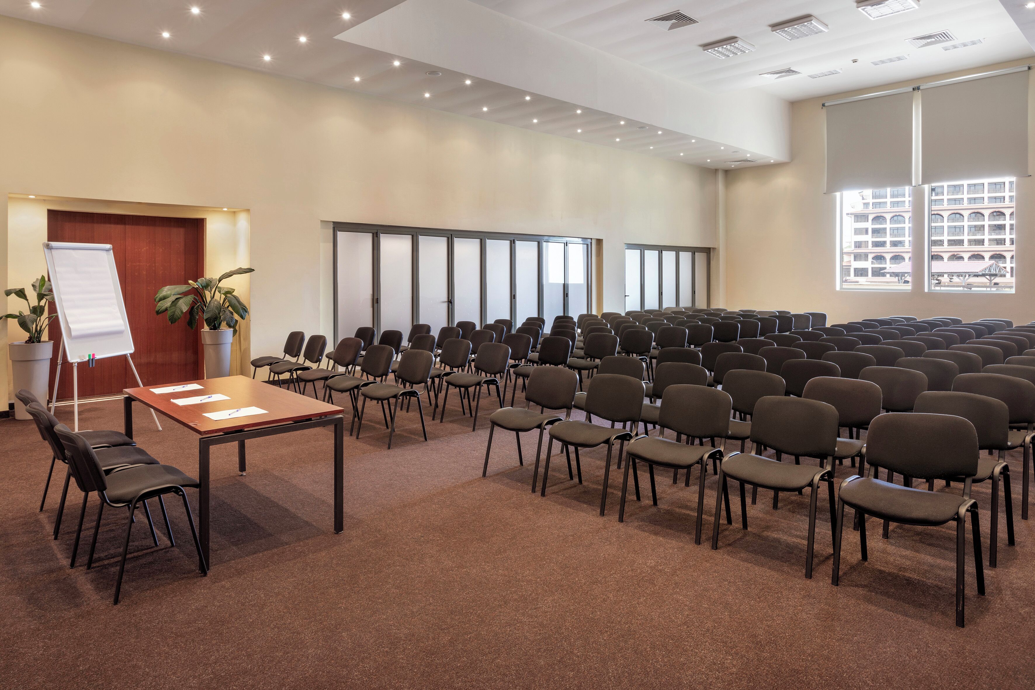 A conference room with rows of chairs, a whiteboard, and a plant.