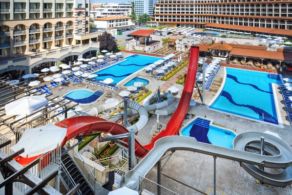 Un hôtel doté de plusieurs piscines, d’un toboggan aquatique et de chaises longues.