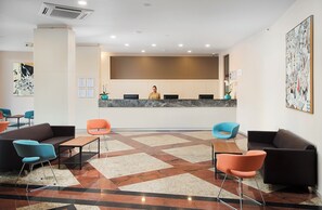 A reception area with a receptionist desk, multiple seating options including sofas and chairs, a patterned floor, and artwork on the walls. - Meliá Sunny Beach Resort (Sunny Beach)