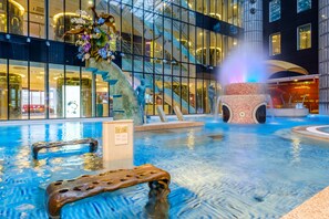 A swimming pool with a statue, a fountain, and a modern building in the background.