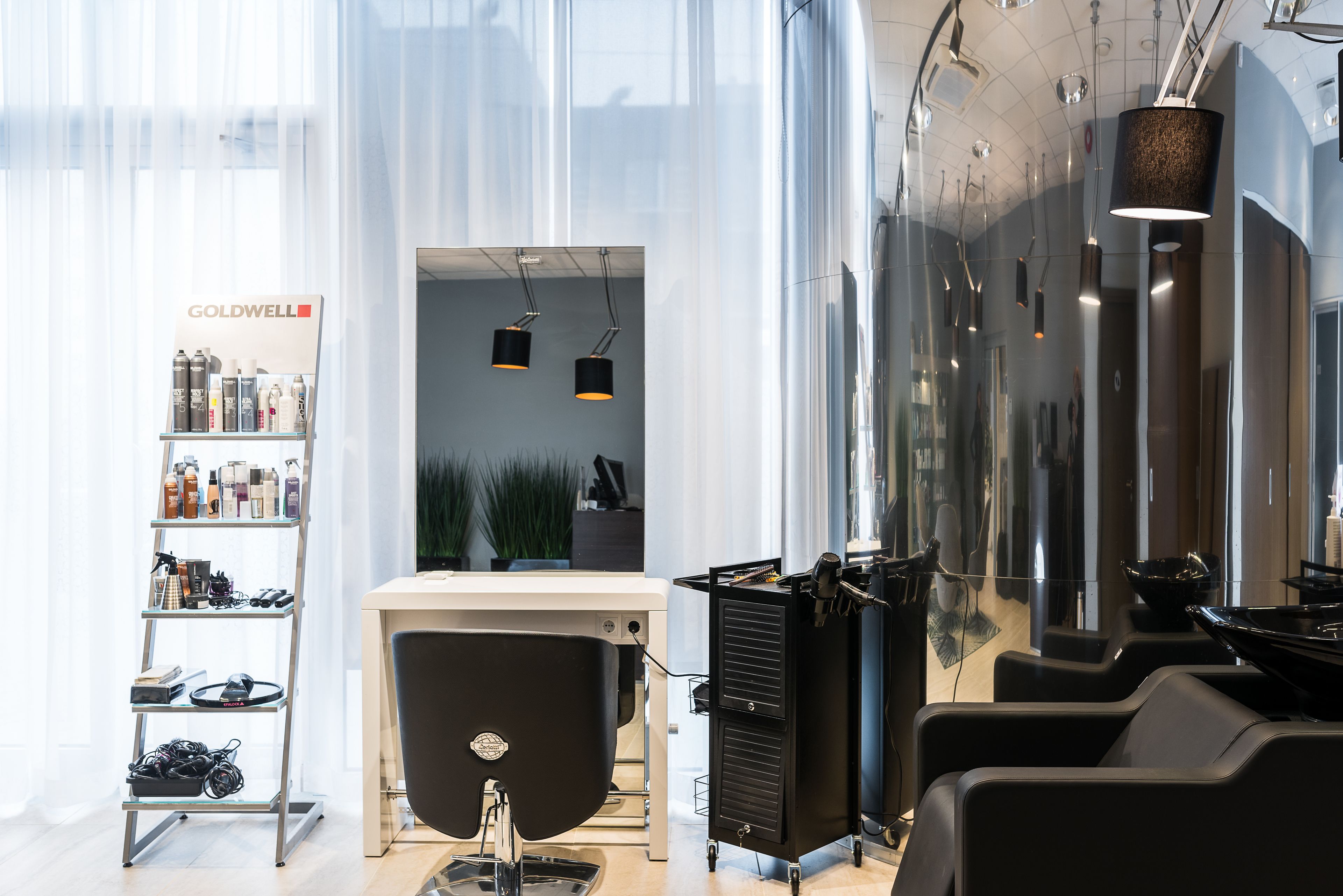 Ein moderner Friseursalon mit Waschbecken, Regalen für Haarpflegeprodukte und einer Sitzecke.