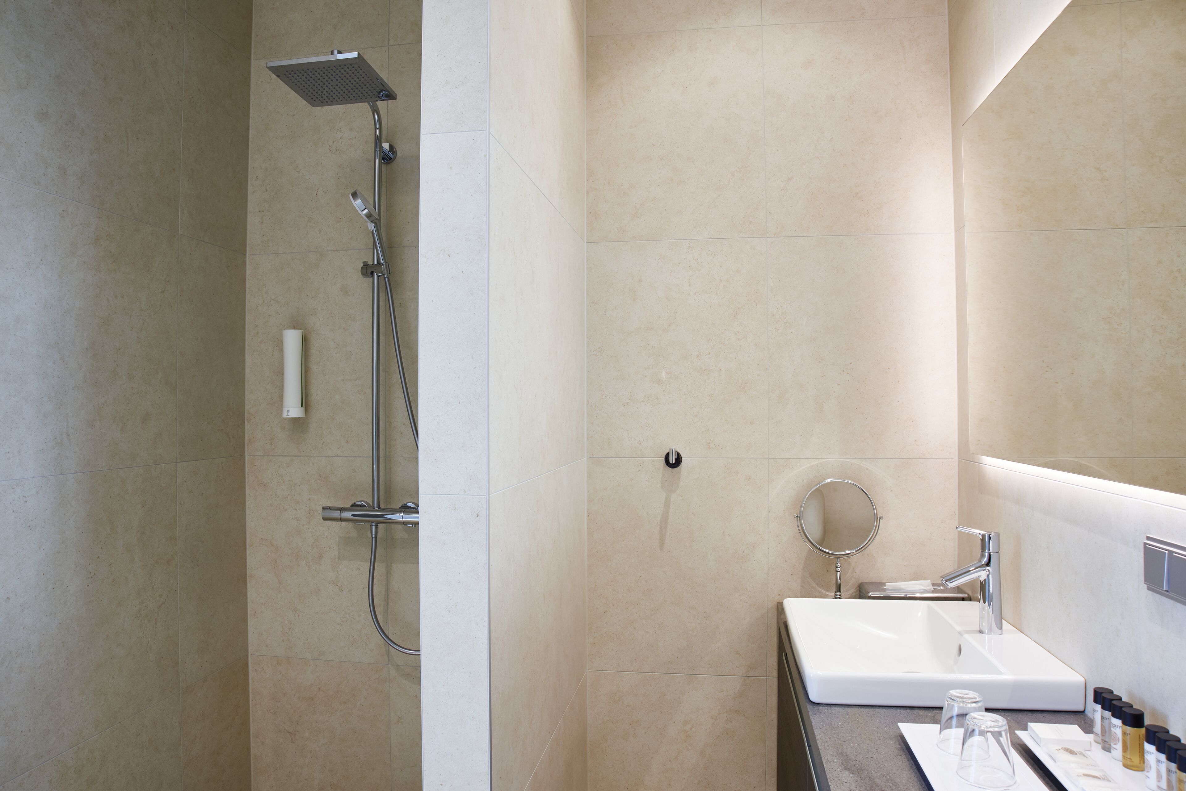 Un baño moderno con ducha, lavamanos y espejo.