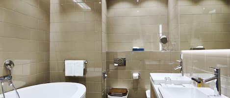 Un baño moderno con una bañera independiente, un inodoro con asiento de madera y un tocador con espejo.