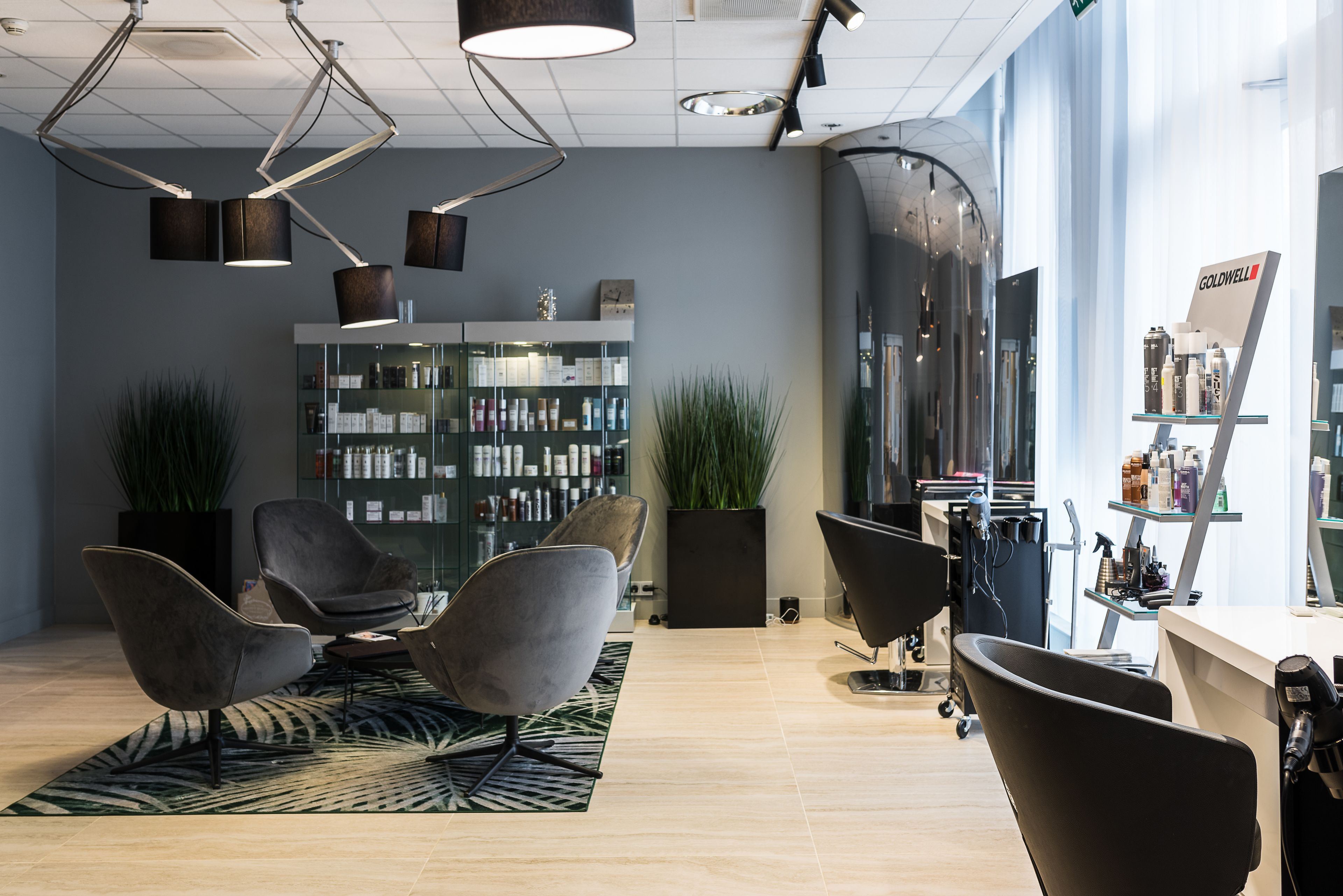 A modern salon interior with contemporary chairs, a large mirror, and a well-organized product display.