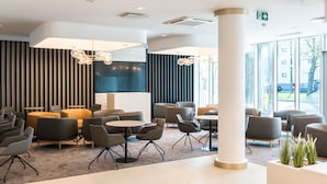 A modern lobby with seating areas, a large pillar, and a view of the outdoors. - Tallink Spa and Conference Hotel (Tallinn)