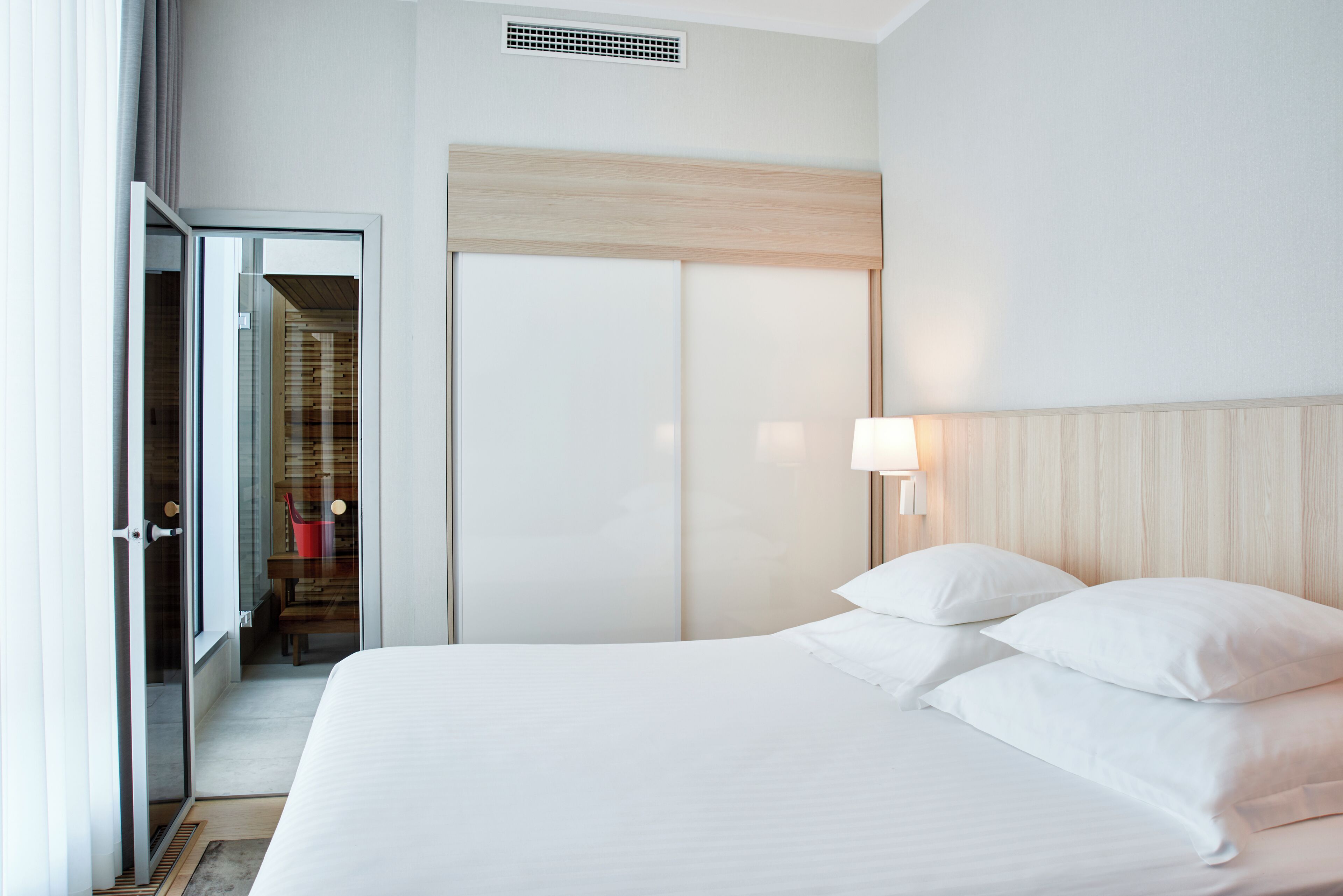 Habitación de hotel con cama, armario, baño y vistas al exterior.