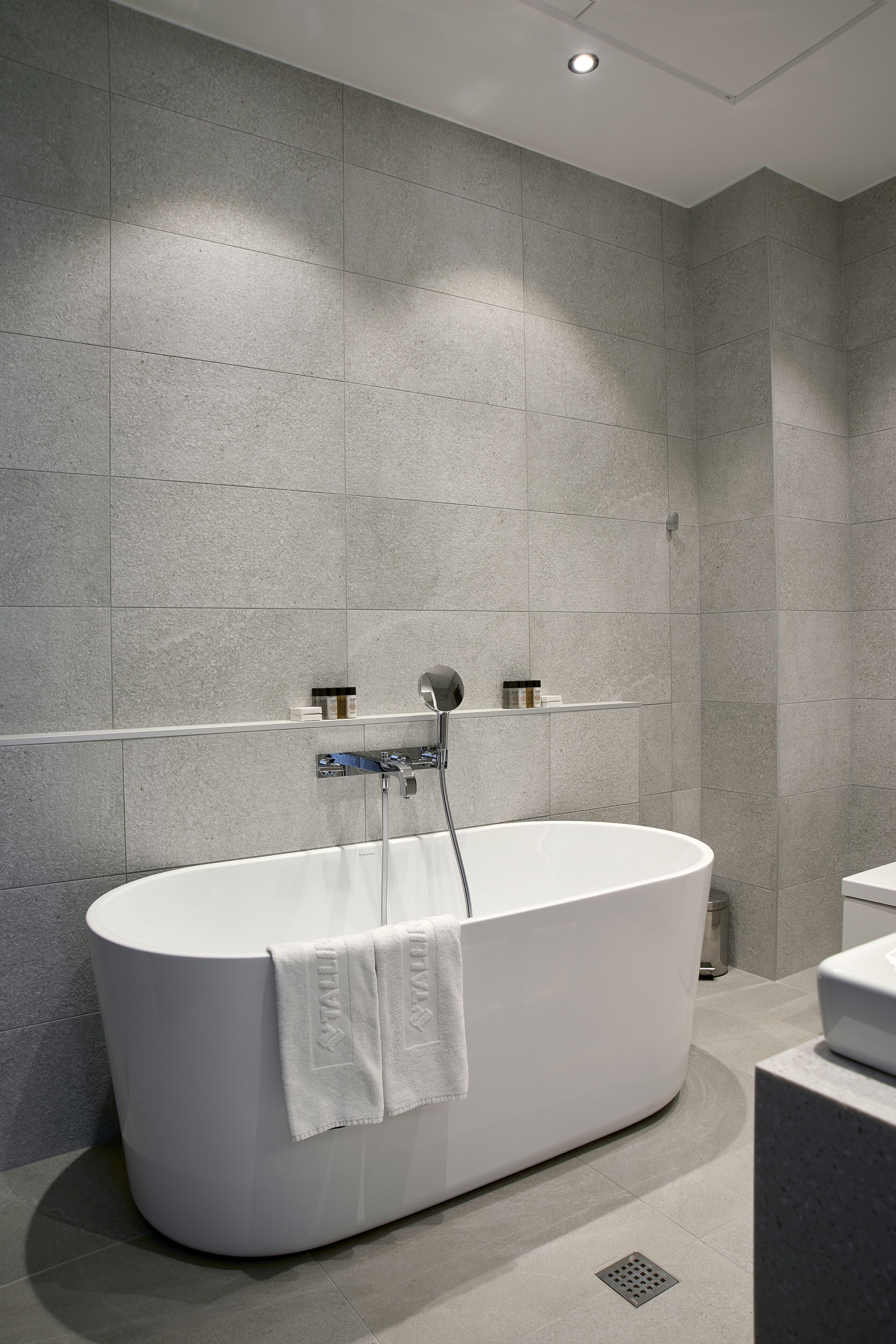 A modern bathroom with a freestanding bathtub, a showerhead, and a towel rack.