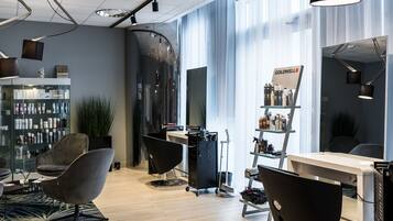 Een moderne salon met een glazen wand, een receptie en diverse haarproducten op planken.