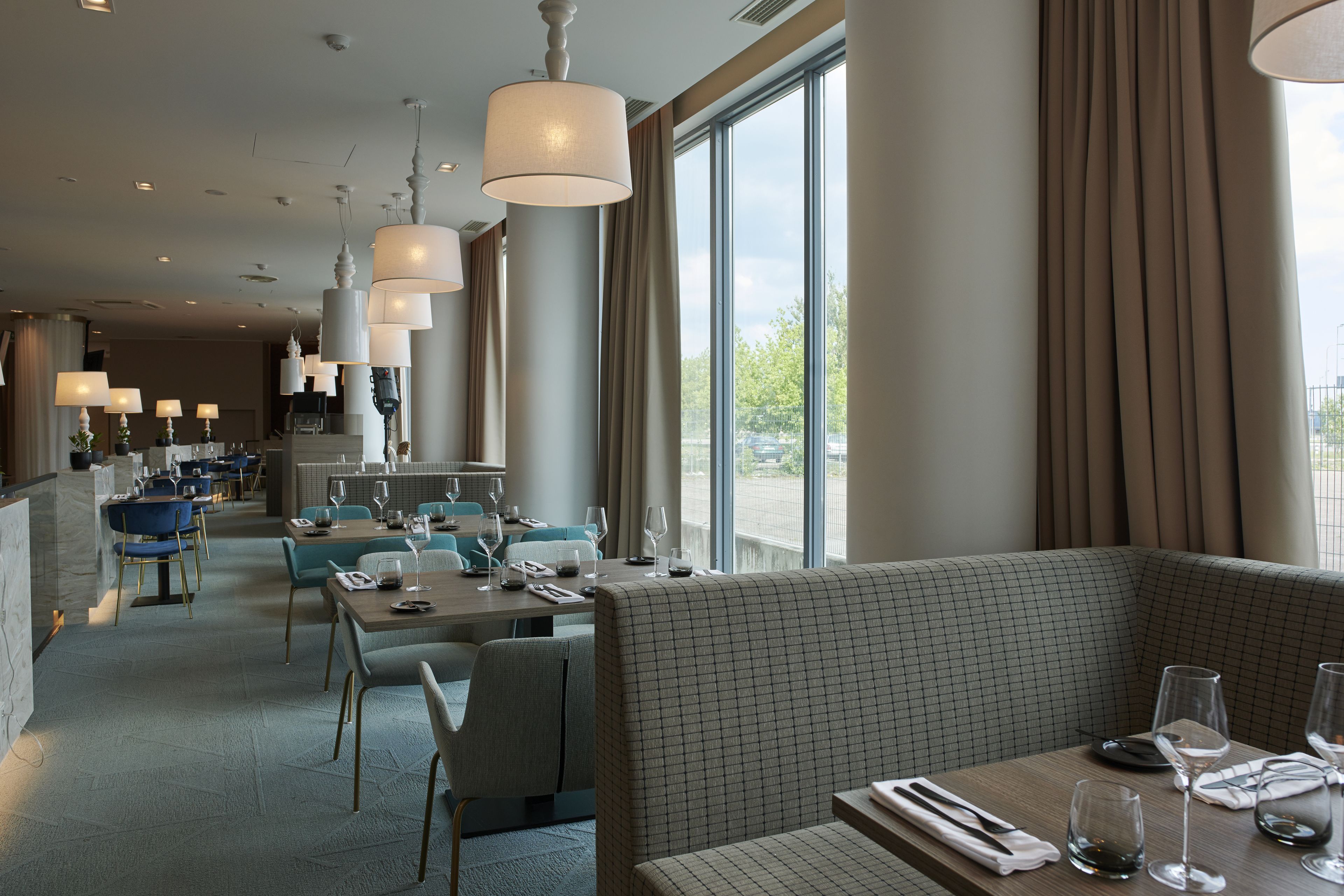 A modern restaurant with high ceilings, pendant lighting, and a view of the outdoors.
