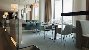 A modern dining area with a glass partition, a table set for four, and a city view through large windows. - Tallink Spa and Conference Hotel (Tallinn)