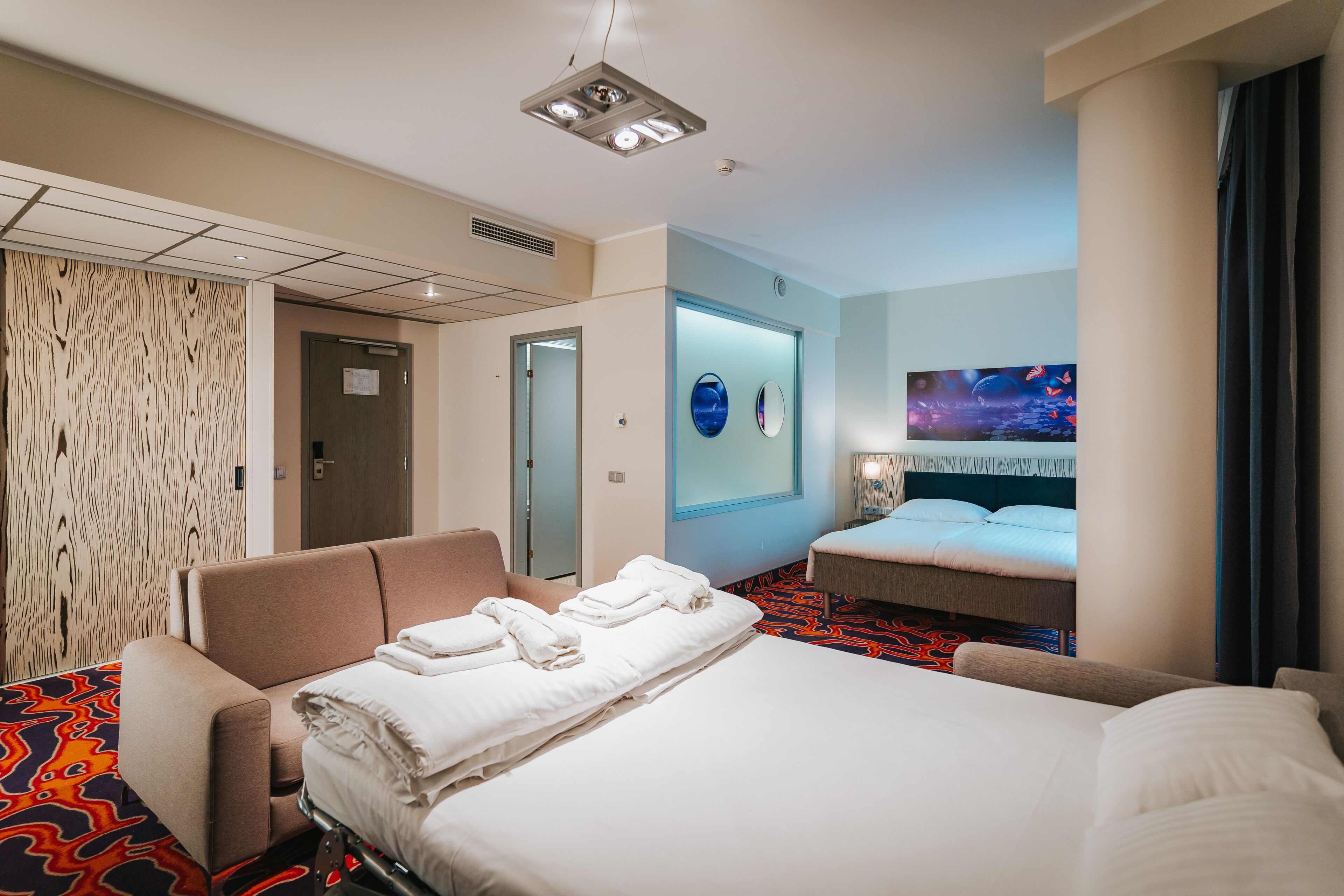 A hotel room with a bed, a sofa, a desk, and a bathroom.