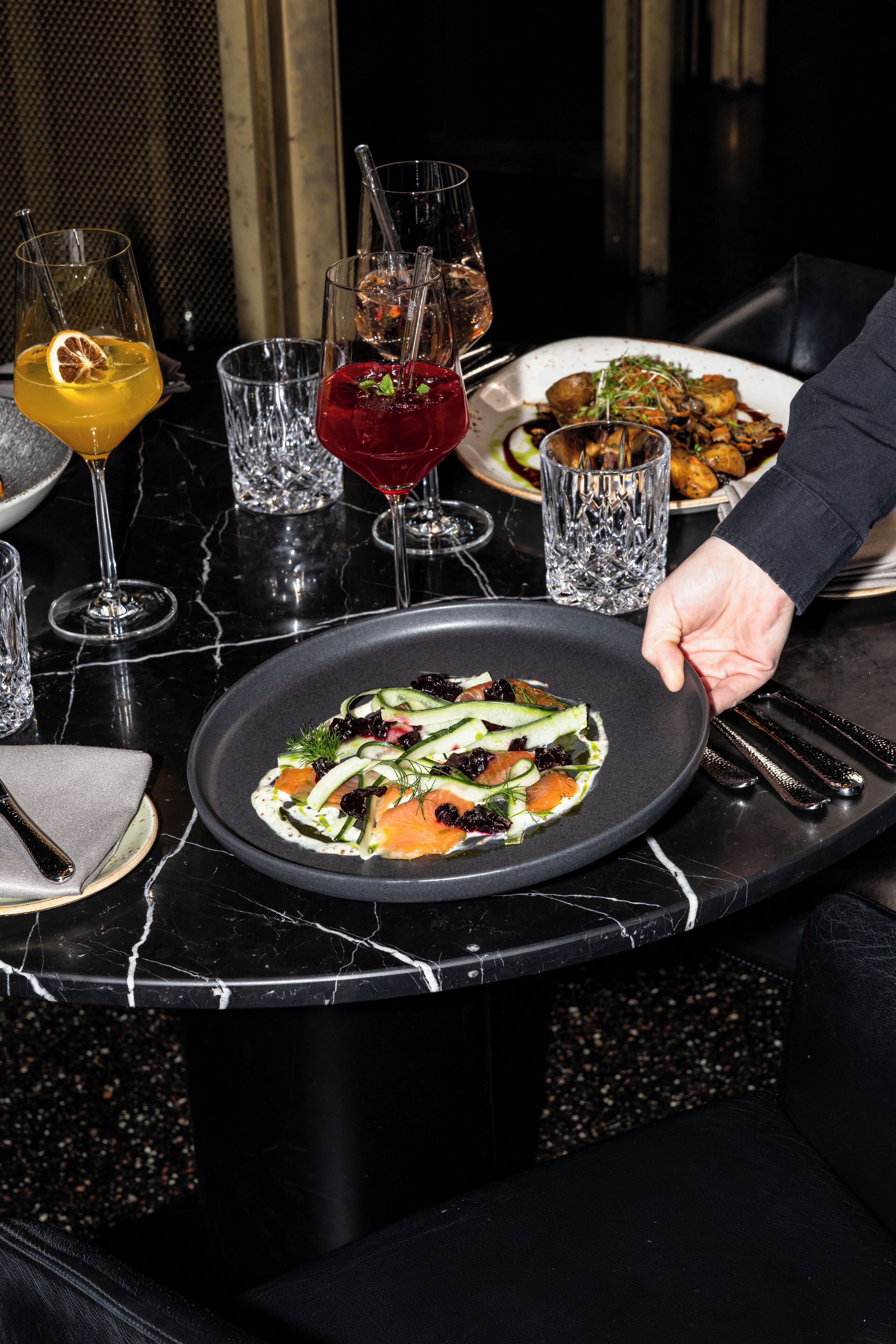 A dining table with a variety of dishes and drinks, including a plate of food and several glasses of different beverages.