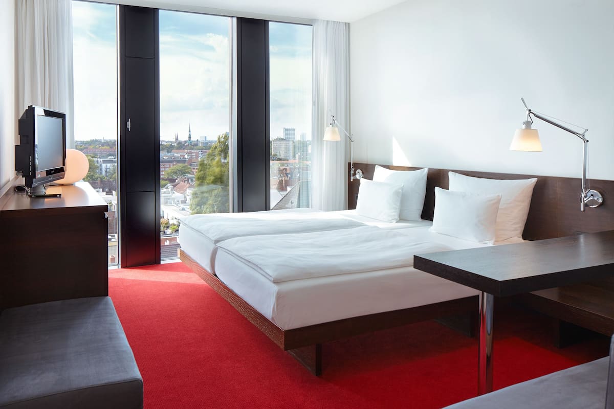 A hotel room with a large bed, a desk, and a TV.