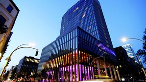 A modern high-rise building with a glass facade and illuminated interior. - Empire Riverside Hotel (Hamburg)