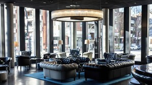 A spacious lobby with leather sofas, a large chandelier, and large windows offering a view of the city. - Empire Riverside Hotel (Hamburg)