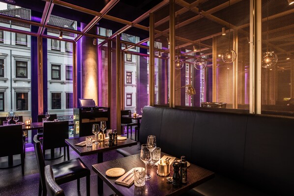Un restaurante con mesas dispuestas para comer, una zona de bar y vistas a edificios.