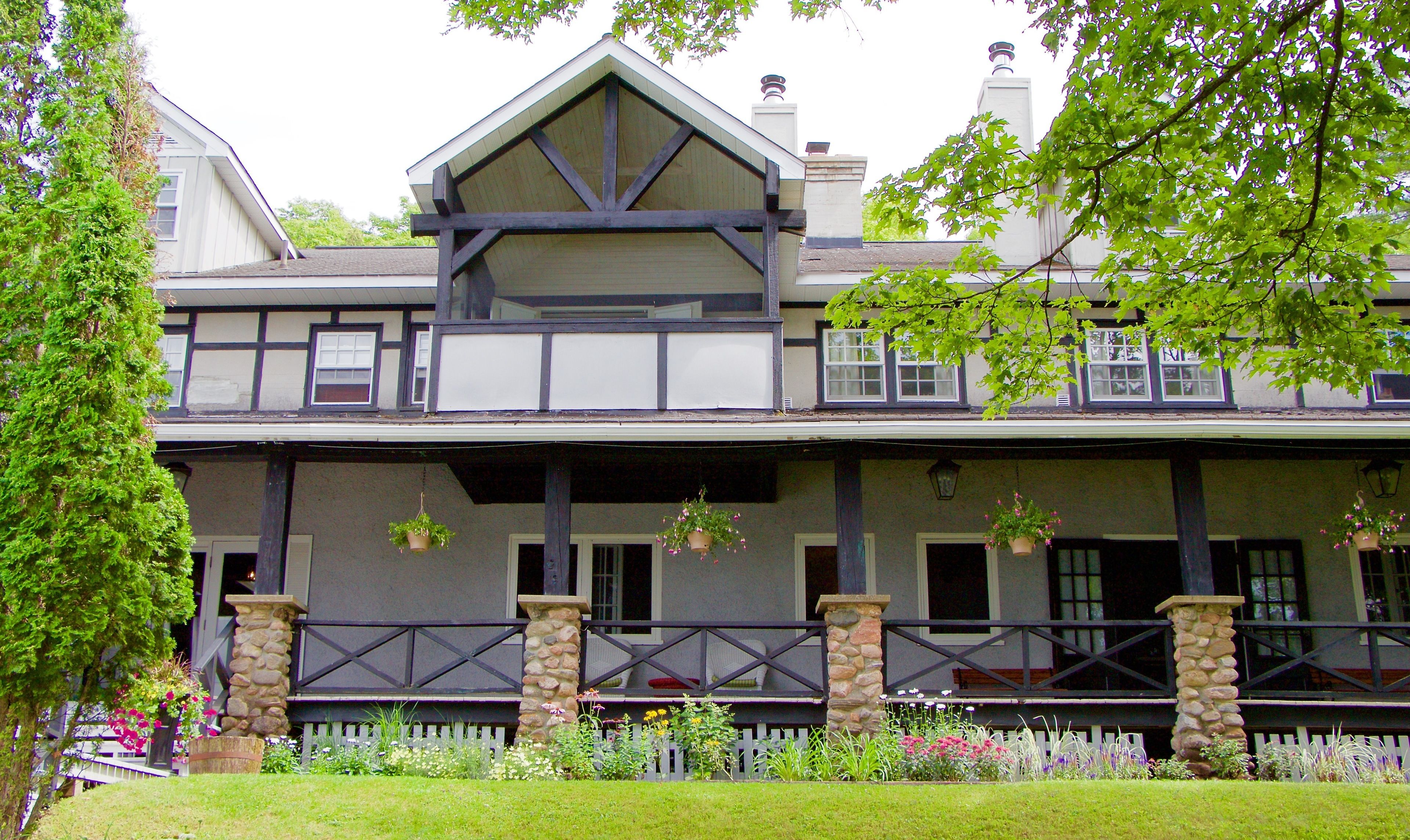 A two-story house with a balcony, stone pillars, and a picket fence.