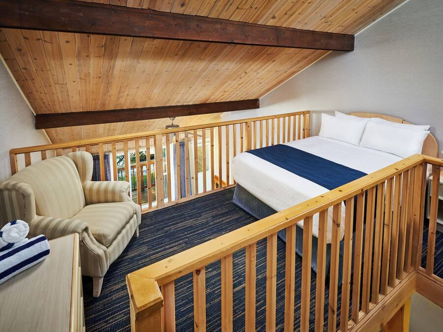 Een slaapkamer met een bed, een stoel en een houten leuning.