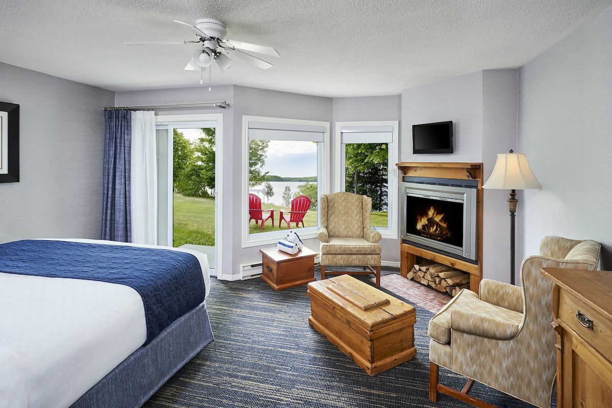 Een hotelkamer met een bed, een open haard, een televisie en uitzicht op de omgeving.