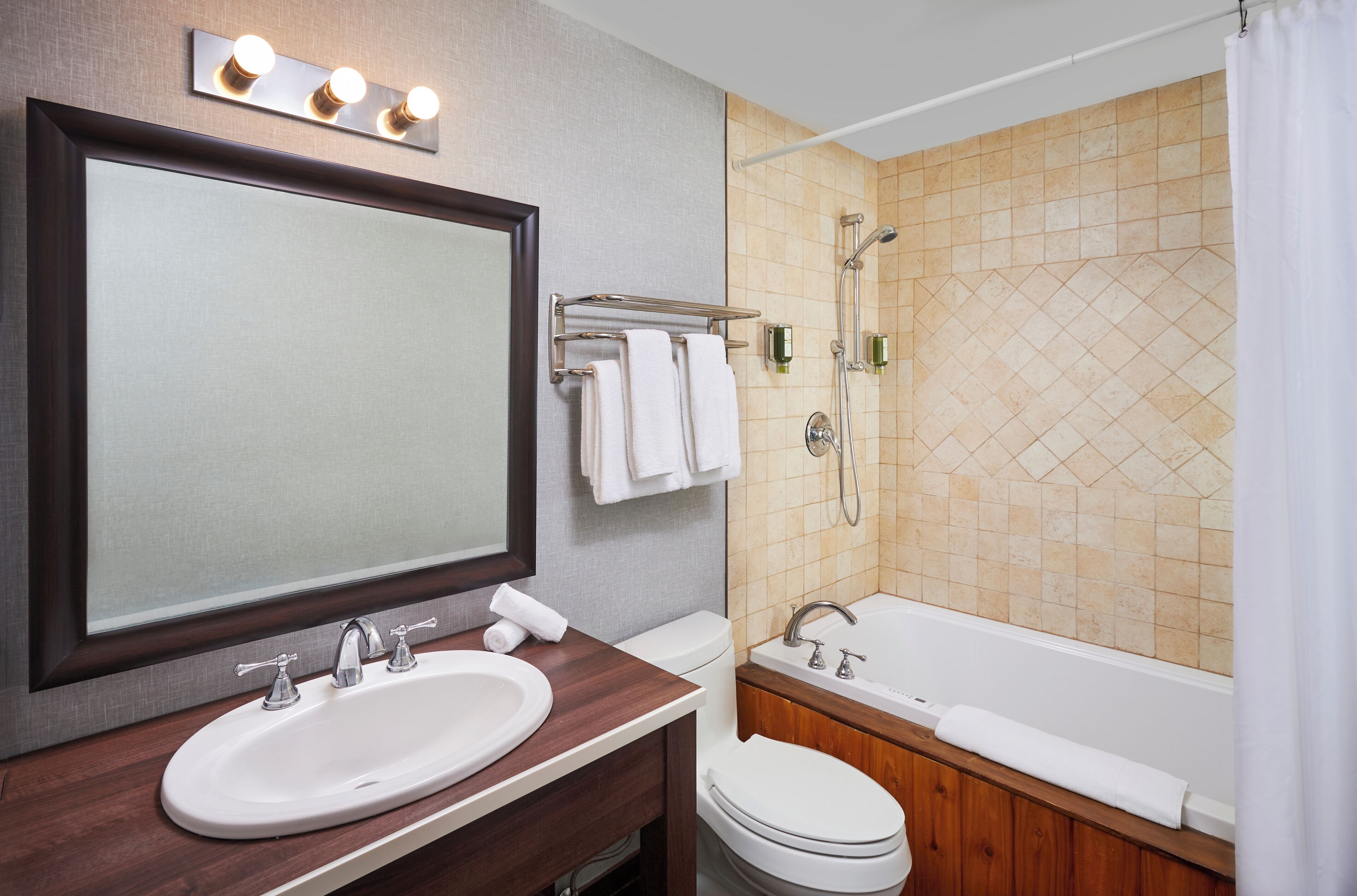 A bathroom with a sink, mirror, toilet, and bathtub.