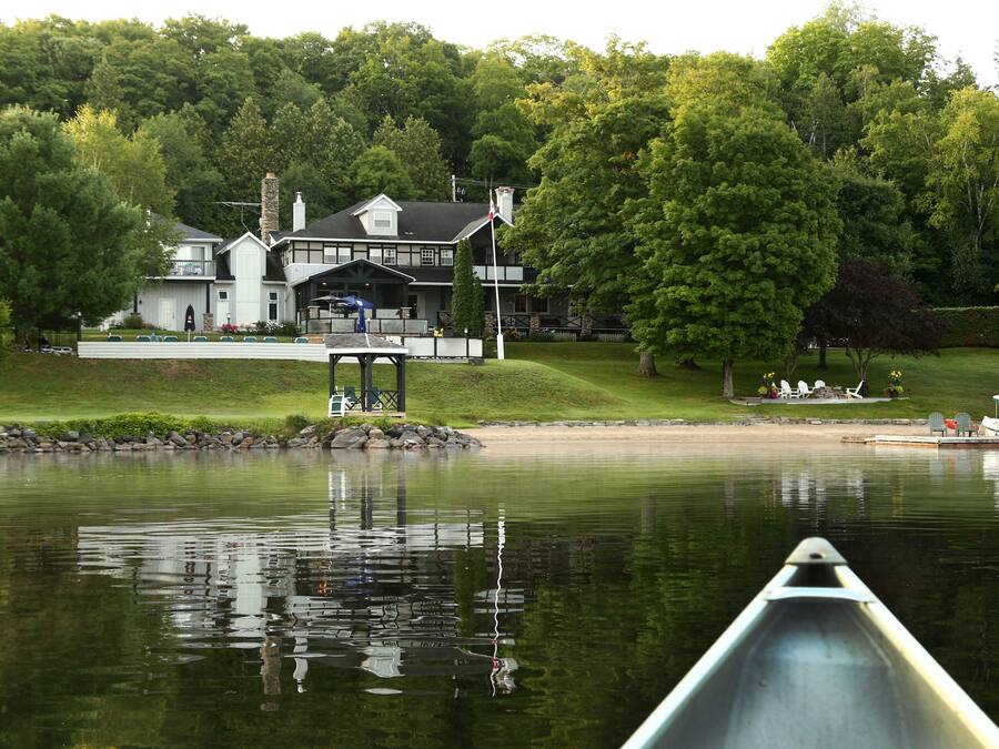 A lakeside property with a large house, a dock, and a canoe.