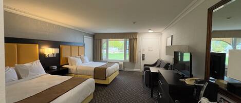 A hotel room with two beds, a desk with a computer, a TV, and a large mirror.