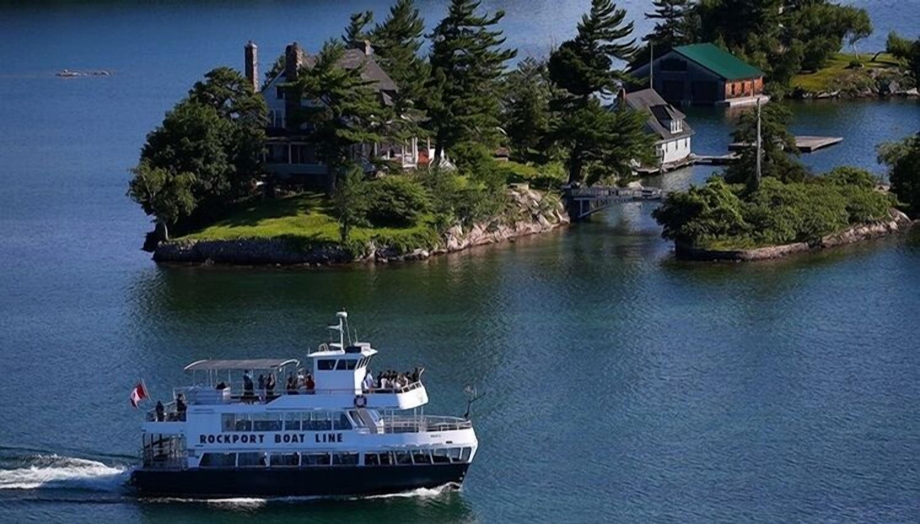 A boat with "ROCKPORT BOAT LINE" on its side, traveling on a body of water with a small island in the background.
