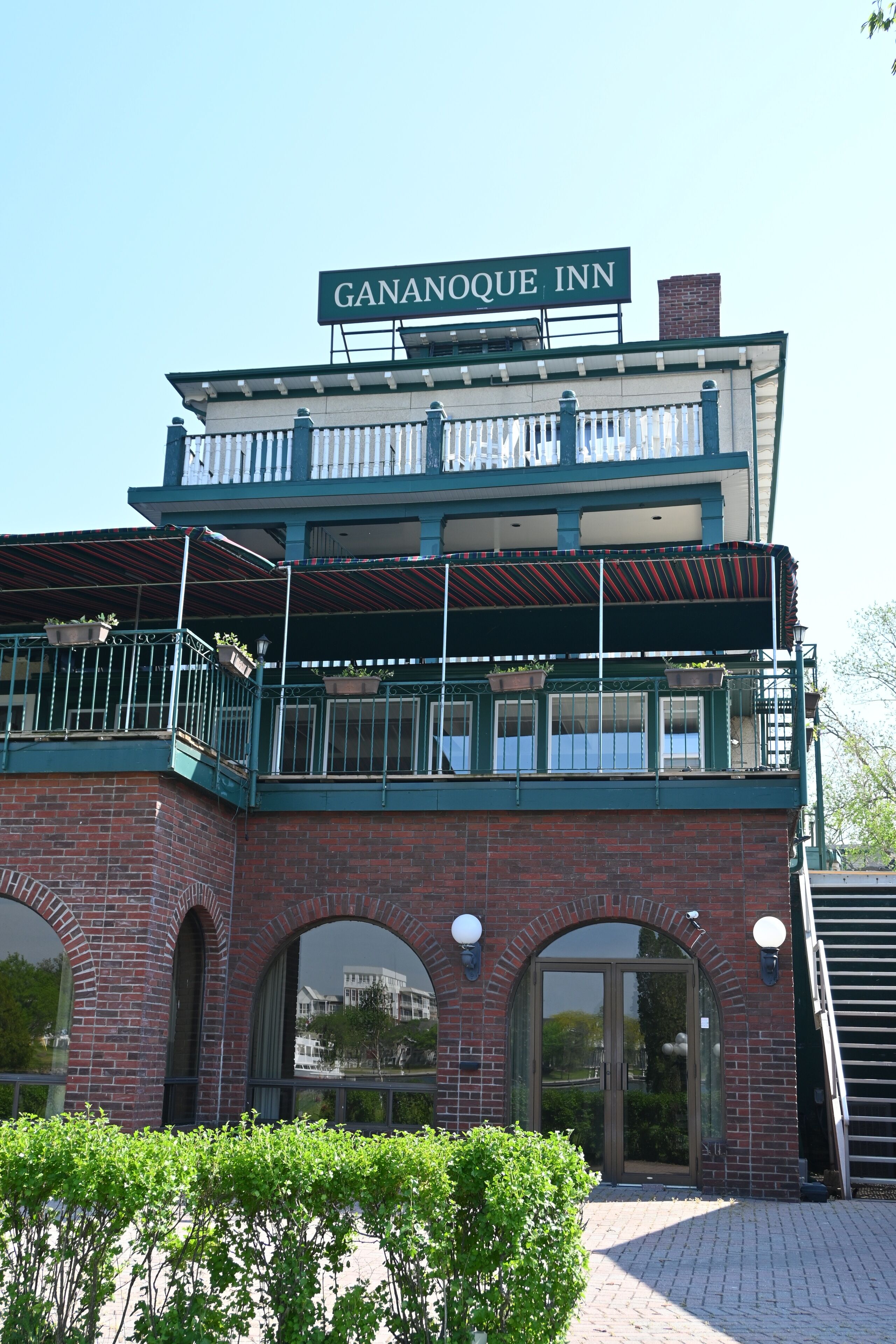 Un edificio de dos pisos con un cartel que dice 'GANANOQUE INN' sobre la entrada.