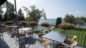 A deck with outdoor seating and a view of a lake. - The Gananoque Inn (Gananoque)