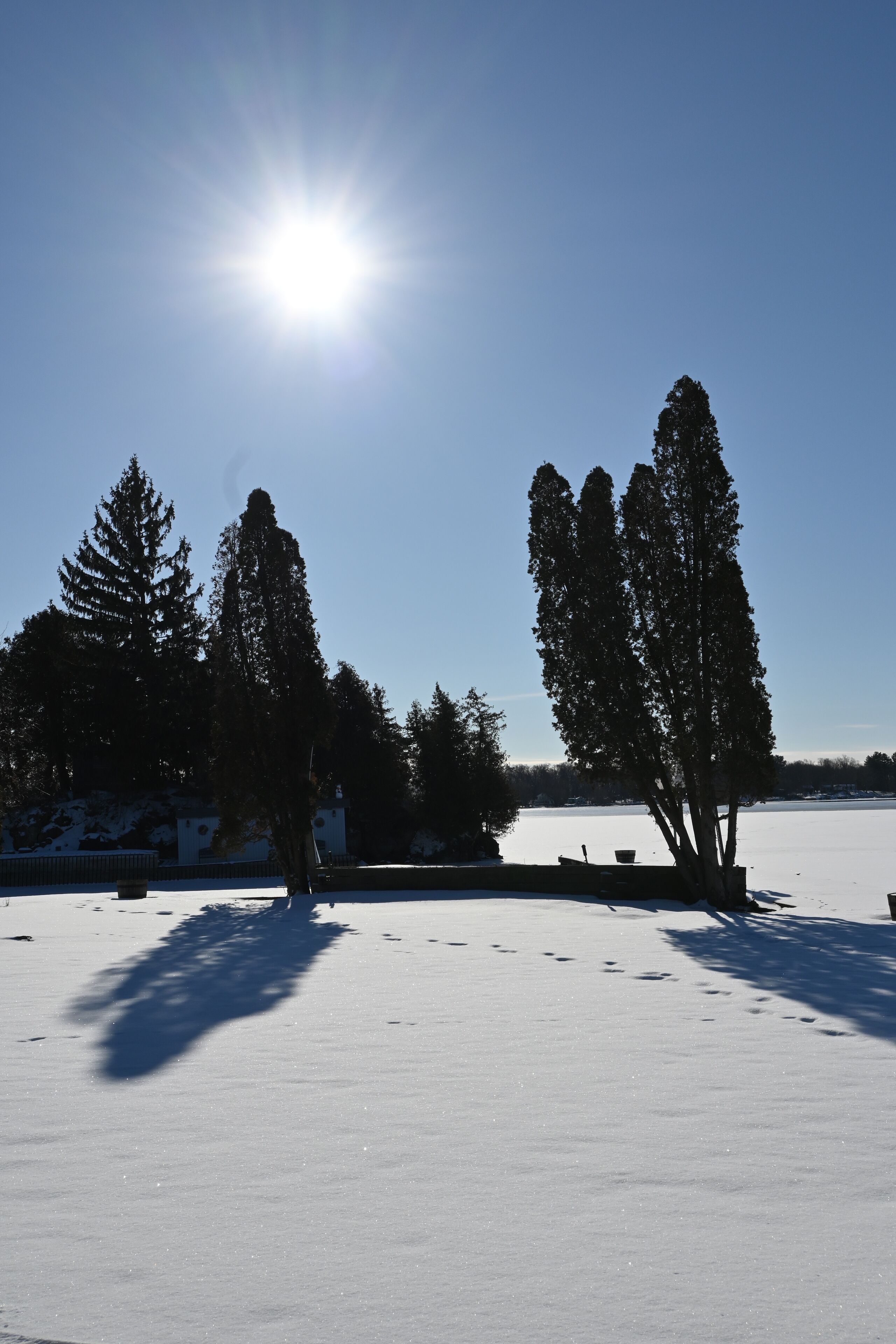 Eine verschneite Landschaft mit klarem Himmel und strahlender Sonne.