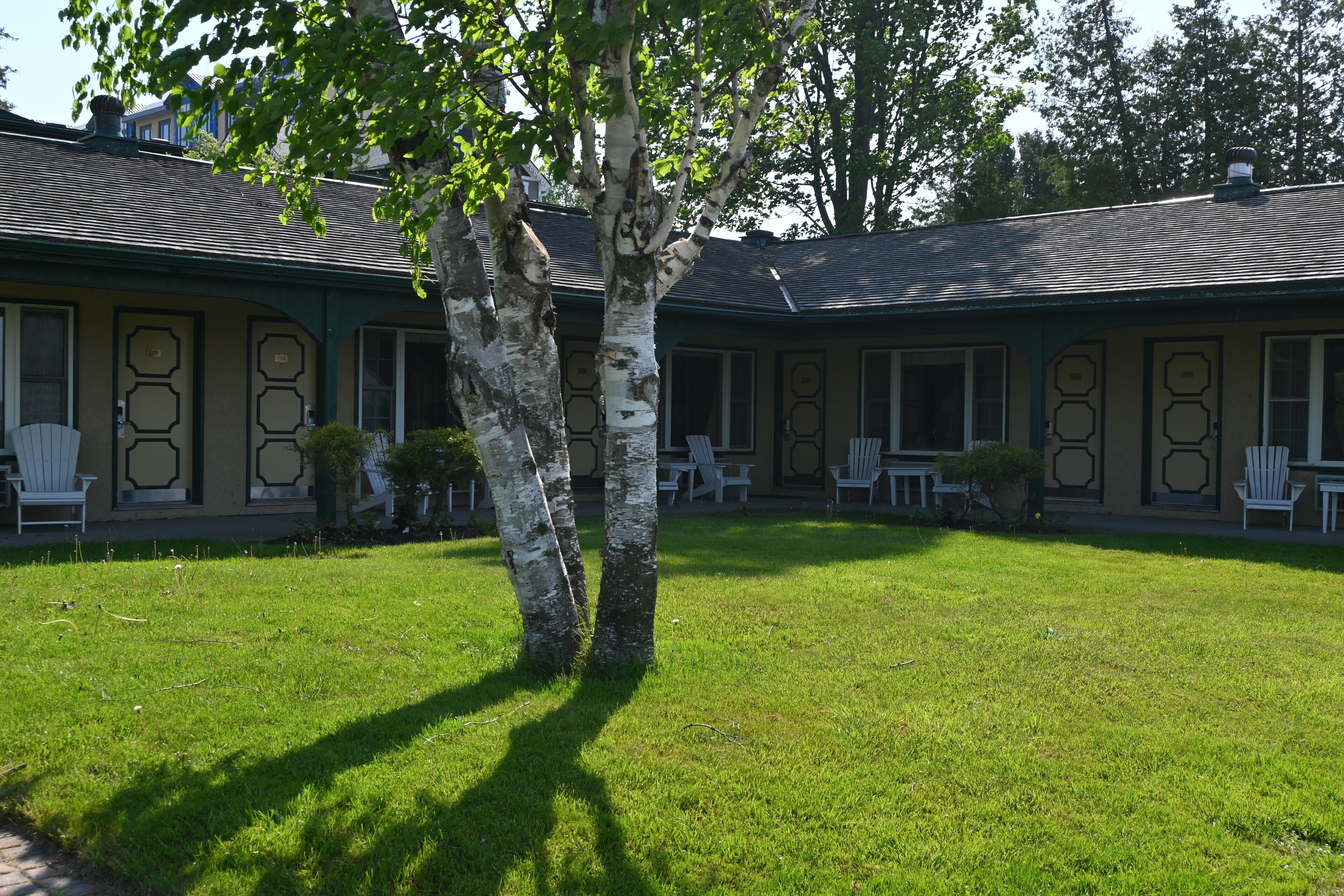 A building with a symmetrical facade, multiple windows, and a well-maintained lawn.
