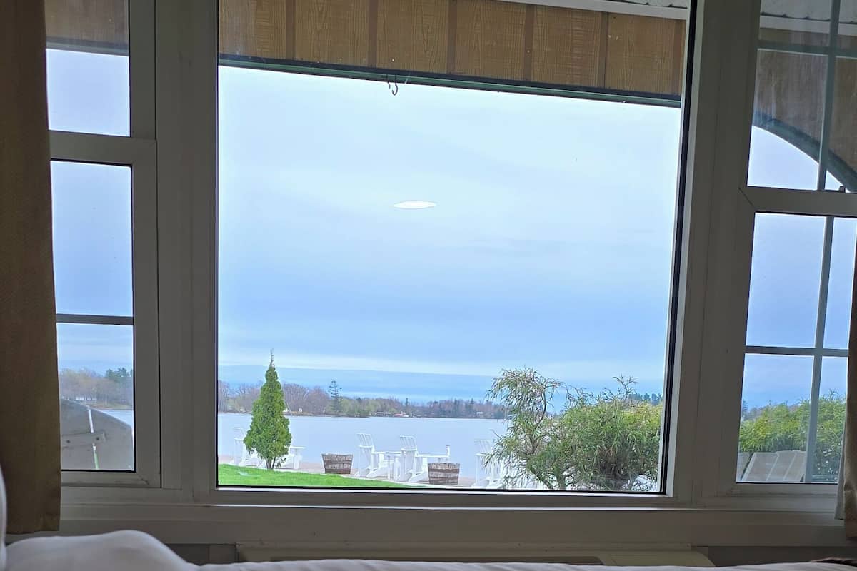 Quarto com uma grande janela com vista para um lago e mobiliário de exterior.