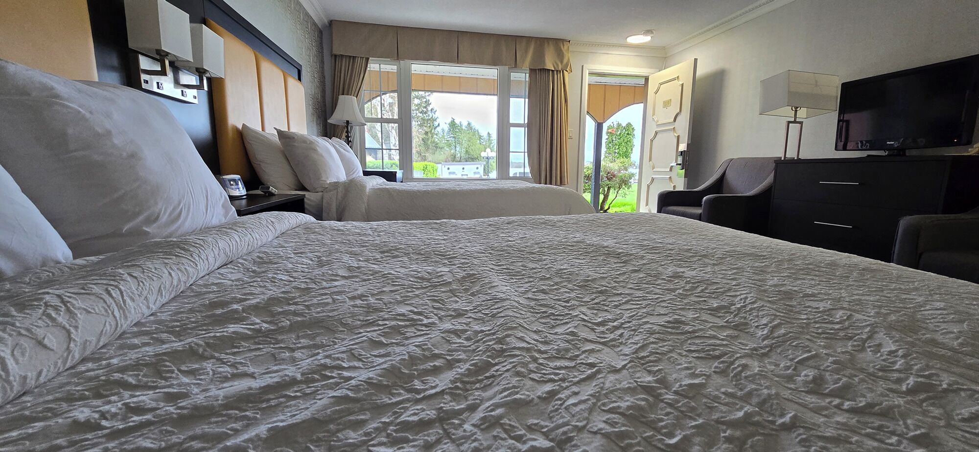 A hotel room with a large bed, a desk, a chair, and a television.