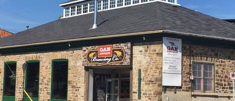 A brick building with a sign for Gan Anquoe Brewing Co. and an ATM sign.