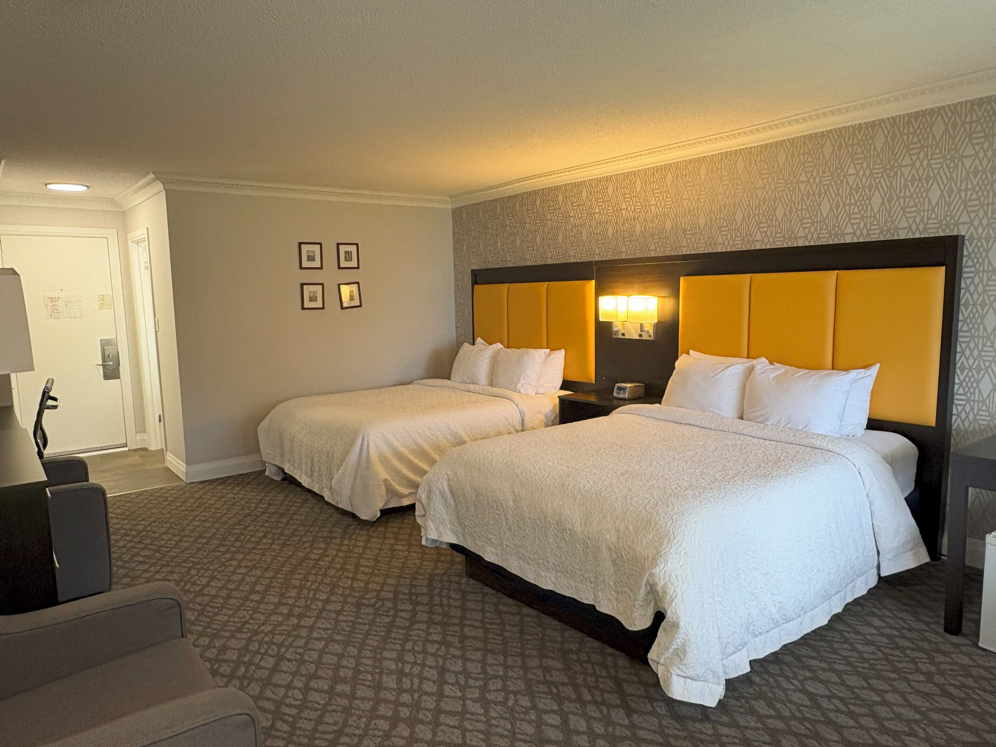 Ett hotellrum med två sängar, ett skrivbord och en mönstrad matta.