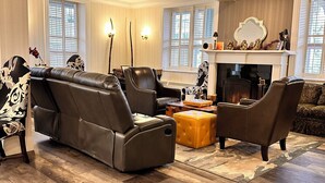A living room with a fireplace, leather sofas, and a patterned rug. - The Gananoque Inn (Gananoque)