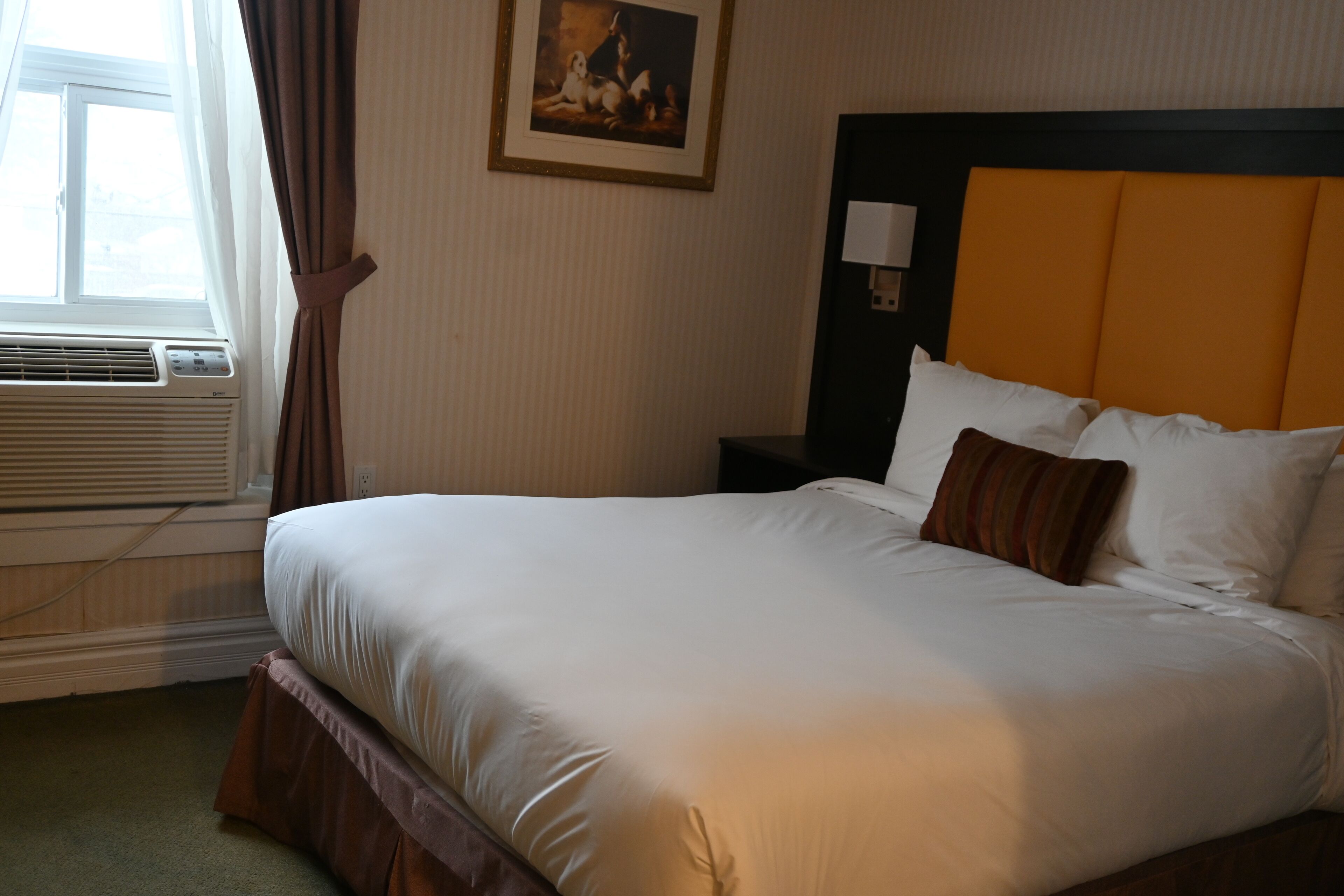 Habitación de hotel con una cama grande, una mesita de noche, una lámpara y un cuadro en la pared.
