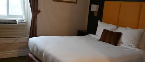 Habitación de hotel con una cama grande, una mesita de noche, una lámpara y un cuadro en la pared.