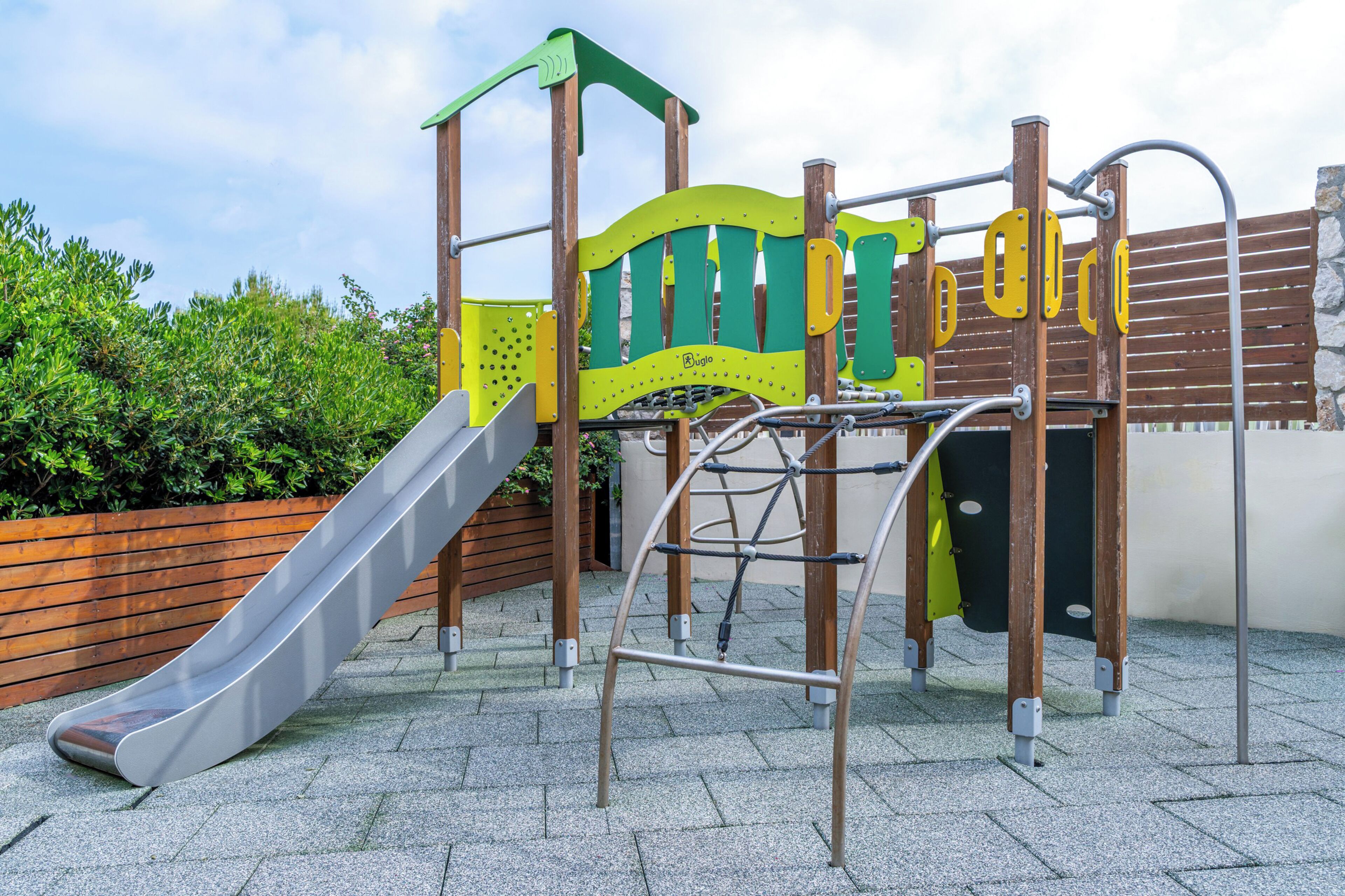 Un parque infantil con un tobogán, estructuras para escalar y una cerca de madera.