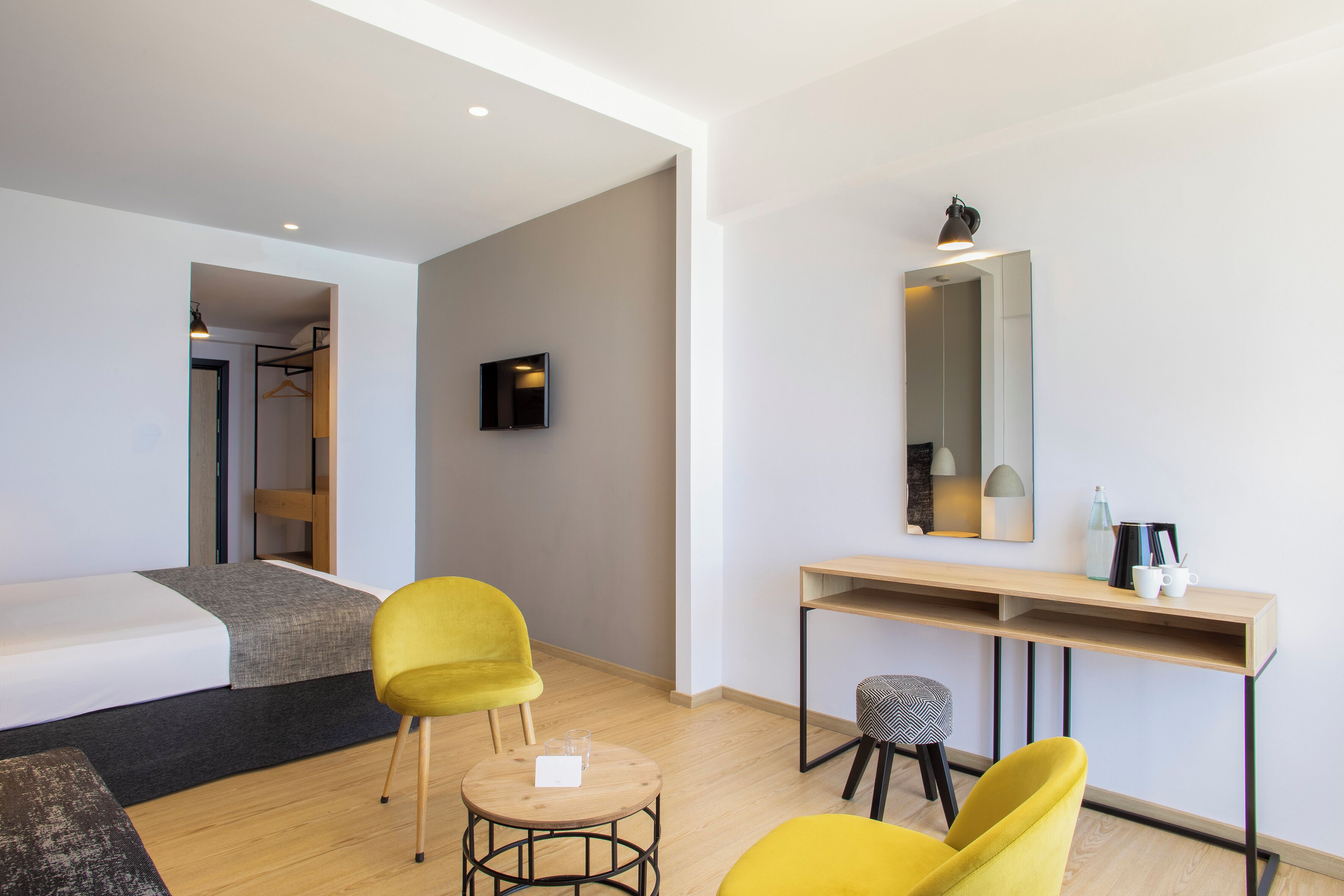 Una habitación de hotel moderna con cama, escritorio, silla y espejo.