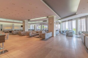 A spacious lobby with multiple seating areas, large windows, and a modern ceiling design. - Sol Cosmopolitan Rhodes - All inclusive (Rhodes)