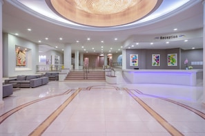 A modern reception area with a reception desk, seating, and a staircase leading to upper floors.