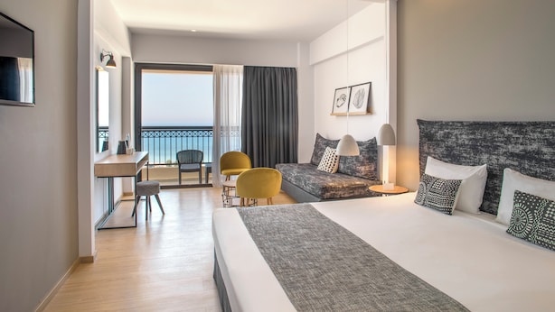 Une chambre d’hôtel moderne dotée d’un grand lit, d’un bureau, d’un canapé et d’un balcon avec vue.