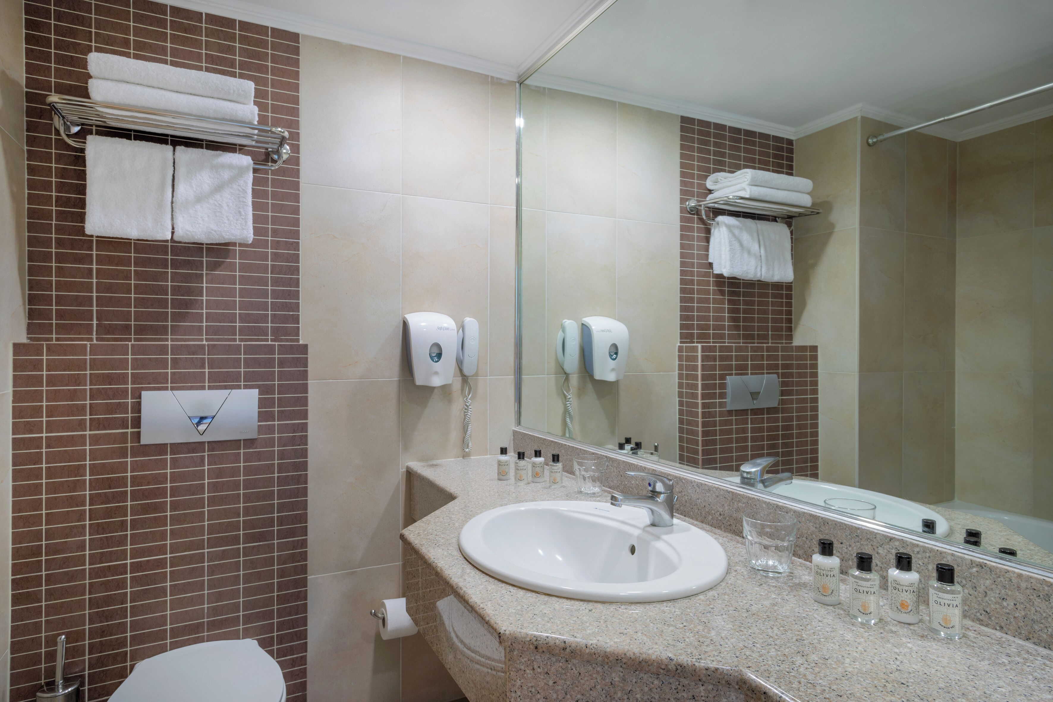 A bathroom with a sink, mirror, towel rack, and toiletries.