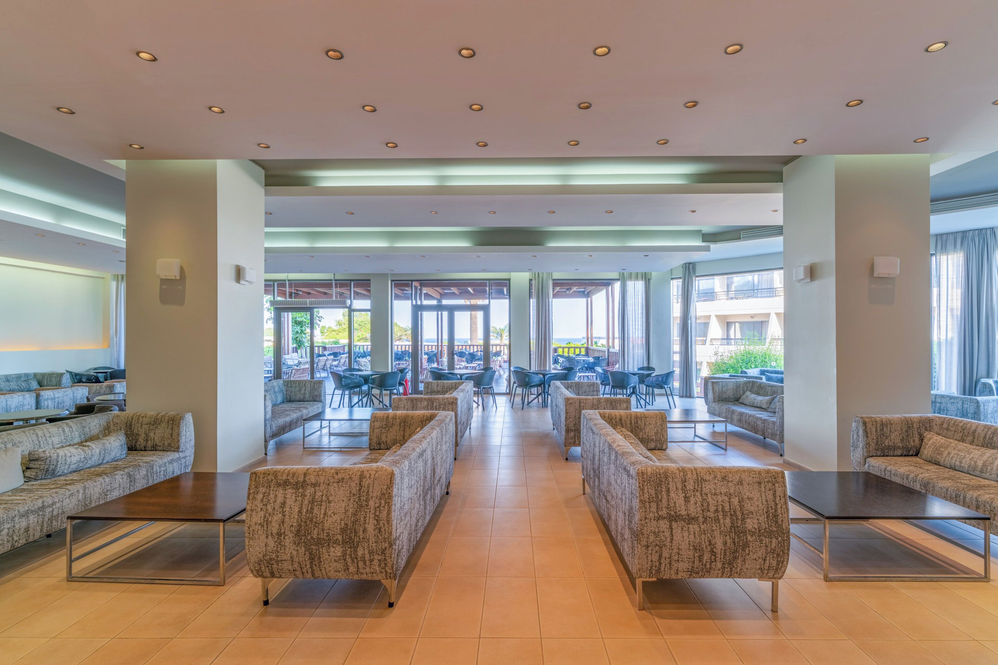 A spacious indoor area with multiple seating arrangements, including sofas and chairs, and large windows providing natural light.