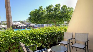 Une terrasse avec des sièges extérieurs, une piscine et une végétation luxuriante.