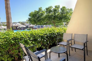 A terrace with outdoor seating, a pool, and lush greenery.