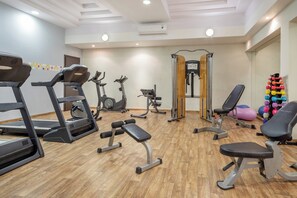 Un gimnasio con cintas de correr, elípticas, bancos de pesas y una variedad de mancuernas.